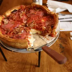 Gruba pizza z ciągnącym się serem i pepperoni, gotowa do podania.