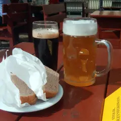 Dwa kufle piwa, ciemne i jasne, oraz chleb na talerzyku. Idealne na letni dzień, by delektować się piwem spiż.