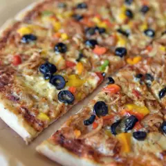Kolorowa pizza z oliwkami i papryką, jakby prosto z podróży po pizze świata.