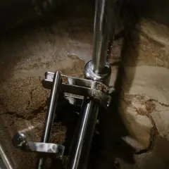 Wnętrze kadzi filtracyjnej z widocznym osadem i elementami mechanicznymi.