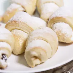 Pyszne, świeżo upieczone rogaliki topione, posypane cukrem pudrem, kuszą swoim wyglądem. Idealne na deser lub do kawy.