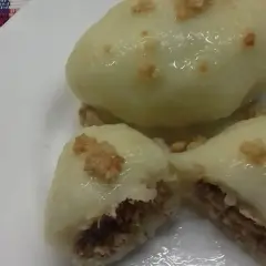 Trzy pyszne cepeliny z mięsem, polane sosem i posypane skwarkami, na białym talerzu.