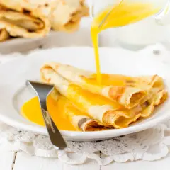 Złociste crepes suzette polane gorącym sosem, gotowe do zjedzenia.