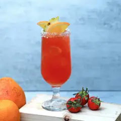 Orzeźwiający drink z pomarańczy i ananasa, z solą na brzegu kieliszka. Obok leżą truskawki, cytryna i pomarańcza. Idealny na lato, jak piwo cytrynowe.