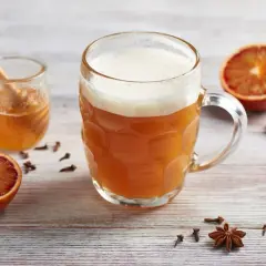 Miodowe piwo w kuflu, obok słoiczek z miodem, pomarańcze, cynamon i anyż. Idealne na chłodne wieczory.