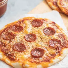 Pyszna pizza z tortilli z pepperoni i serem, obok sos i łyżeczka.