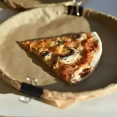 Kawałek pizzy z pieczarkami i serem na papierowym talerzu. Zastanawiasz się, ile kalorii ma pizza pepperoni?