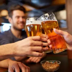 Trzech przyjaciół wznosi toasty. W rękach trzymają szklanki z bursztynowym piwem, a na stole stoi miseczka z orzeszkami. Idealny wieczór z piwem małym mocnym.