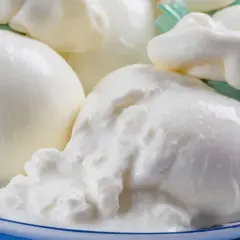 Świeża burrata, co to jest? Delikatny ser mozzarella z kremowym wnętrzem, podany na talerzu.