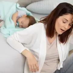 Zmęczona matka z butelką piwa obok śpiącego dziecka. Czy piwo karmi szkodzi?