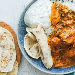 Pyszny kurczak butter masala z ryżem, jogurtem i chlebkami naan.
