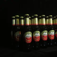 Rząd butelek piwa Amstel na czarnym tle. Zastanawiasz się, ipa co to? To piwo, które warto spróbować.