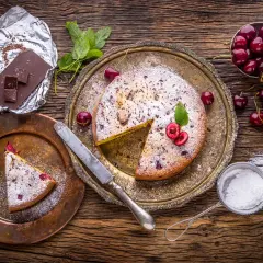 Pyszny kawałek ciasta drożdżowego z wiśniami, posypany cukrem pudrem. Idealny deser, choć warto pamiętać o jego kcal.