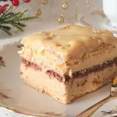 Pyszne ciasto z budyniem, przełożone kremem i polane lukrem. Idealne na święta, z gałązką choinki w tle.