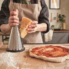 Osoba trze ser na pizzę. Zastanawiasz się, czy ciasto na pizzę może się zepsuć? Nie martw się, świeży ser to klucz do sukcesu!