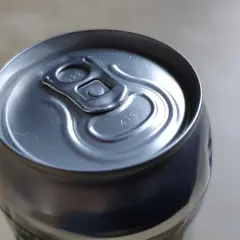 Metalowa puszka piwa z widocznymi kropkami na wieczku, które mogą oznaczać datę produkcji lub numer partii.