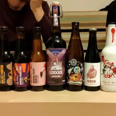 Rząd butelek z piwem, w tym mocne piwo, z etykietami "Piwojad", "Baltic Porter", "Imperial Pastry Stout", "Szkockie", "Igroki" i "Perła".