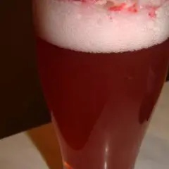 Czerwone piwo z sokiem, z obfitą pianką i kawałkami owoców na wierzchu. Idealne na letnie popołudnie.
