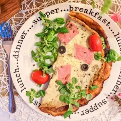 Pyszne, sycące śniadanie do pracy: omlet z szynką, pomidorkami i oliwkami, udekorowany świeżą sałatką.