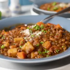 Syci wege gulasz z soczewicy, ziemniaków i marchewki, posypany natką pietruszki i parmezanem.