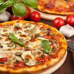 Pyszna pizza z cukinią, oliwkami i pomidorkami, obok surowe pieczarki na pizze, czosnek i bazylia.