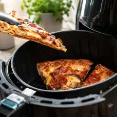 Jak odgrzać pizzę na patelni? Włóż kawałki pizzy do frytkownicy beztłuszczowej, aby uzyskać chrupiący spód i idealnie roztopiony ser.