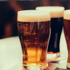 Trzy kufle piwa z pianką. Jasne i ciemne piwo, które może przynieść wiele zalet.