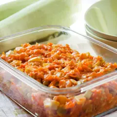 Pyszny bigos z cukinii w szklanym naczyniu, obok świeże cukinie i miseczki.