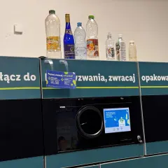 Na automacie do zwrotu opakowań stoją puste butelki. Widać, które butelki są zwrotne po piwie i innych napojach.