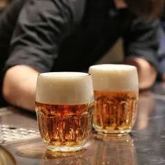 Dwa kufle pysznego czeskiego piwa z gęstą pianką stoją na barze.