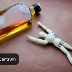 Drewniany ludzik obok butelki z alkoholem. Czy piwo wpływa na testosteron? Keto Centrum.
