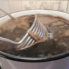 Gotowanie brzeczki do imperial stout. Metalowa chłodnica zanurzona w ciemnym płynie.