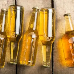 Pięć butelek piwa bezalkoholowego na drewnianym tle. Zobacz, jak powstaje piwo bezalkoholowe.