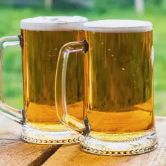 Dwa kufle złocistego piwa z pianką, gotowe do degustacji. Idealne na lato, przypominają o tym, jak zrobić piwo w domowym zaciszu.