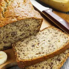 Pyszny chlebek bananowy, pokrojony na kromki, z bananami i nożem na desce.