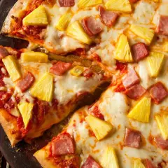 Pyszna pizza z ananasem i szynką, z ciągnącym się serem i sosem pomidorowym. Idealna na letni wieczór.