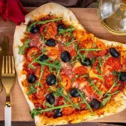 Serce z pizzy z pomidorami, oliwkami i rukolą. Idealna kolacja dla dwojga, z dodatkiem oliwy i przypraw.