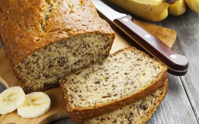 Pyszny chlebek bananowy, pokrojony na kromki, z bananami i nożem na desce.