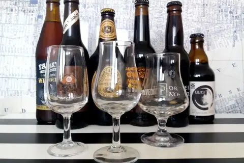Kolekcja butelek i kieliszków do degustacji, prezentująca różnorodne gatunki piwa w Polsce.