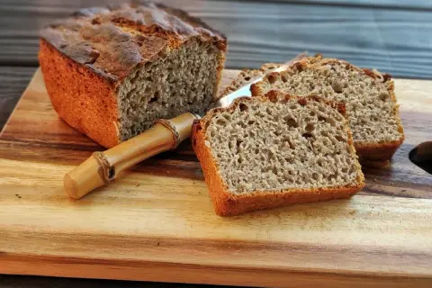 Pyszny, domowy **prosty chleb na zakwasie** pokrojony na kromki, leżący na drewnianej desce.