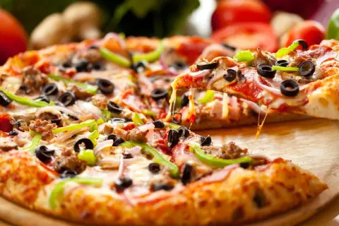 Pyszna pizza na spodzie do pizzy, z ciągnącym serem, oliwkami, papryką i salami. Idealna na spotkanie z przyjaciółmi.
