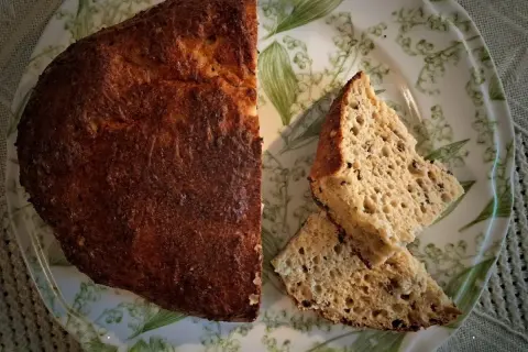 Chleb keto przepis: złocisty bochenek i dwa kawałki na talerzu z konwaliami. Idealny na dietę niskowęglowodanową.