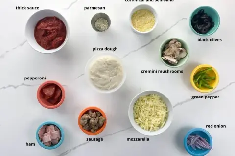 Składniki do pizzy: sos, ser, ciasto, pepperoni, szynka, kiełbasa, pieczarki, oliwki, papryka, cebula, parmezan, mąka kukurydziana.