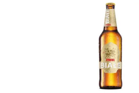 Butelka piwa Żywiec Białe z kroplami rosy na szkle.