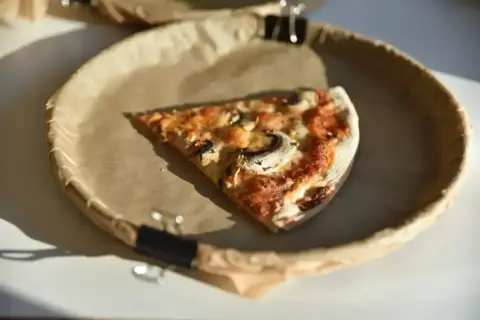 Kawałek pizzy z pieczarkami i serem na papierowym talerzu. Zastanawiasz się, ile kalorii ma pizza pepperoni?