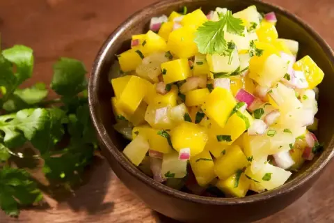 Miseczka pełna świeżej, kolorowej salsy mango z kawałkami mango, cebuli i kolendry. Idealna na letnie dni.