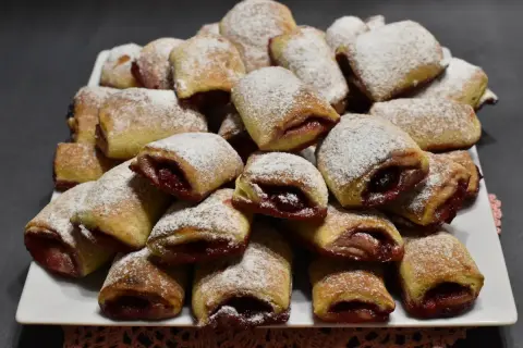Stos ciasteczek z wiśniami, posypanych cukrem pudrem, wygląda apetycznie.