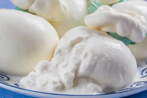Świeża burrata, co to jest? Delikatny ser mozzarella z kremowym wnętrzem, podany na talerzu.