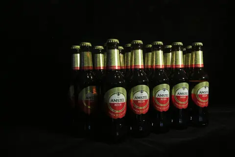 Rząd butelek piwa Amstel na czarnym tle. Zastanawiasz się, ipa co to? To piwo, które warto spróbować.