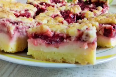 Kruche ciasto z budyniem i owocami wiśni, posypane kruszonką. Pyszny deser na talerzu.